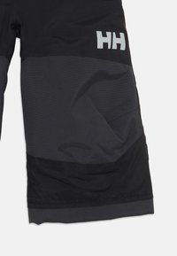 Svart ute shorts med en kontrasterende grå panel, utstyrt med en side lomme og en fremtredende "HH" logo i lys grå.