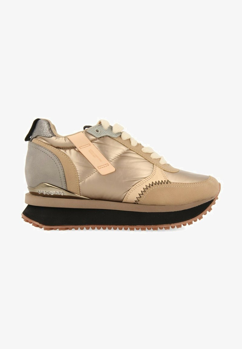 Zapatillas sintéticas y de ante en color beige con un brillo metálico, suela gruesa negra, diseño acolchado y cordones crema. Presenta una etiqueta de la marca en el lateral.