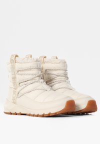 Botas aislantes blancas con textura acolchada, cordones ajustables y suela de goma con detalles en marrón. Marca visible en el lateral.