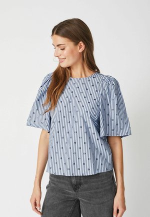 Blusa a righe blu e bianche con maniche a sbuffo, decorata con piccoli pois blu scuro. Realizzata in tessuto leggero, con design a taglio quadrato.