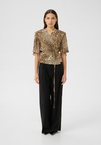 Leopard print blouse with short fluted sleeves, cinched waist, and a tie detail, paired with black wide-leg pants. Smooth fabric texture.