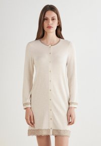 Beige Langarmkleid mit rundem Ausschnitt, vorderer Knopfleiste und gewelltem Spitzenbesatz an den Ärmeln und dem Saum. Weicher, glatter Stoff.