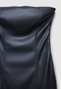 Chaise en cuir noir avec une texture lisse, dossier profilé et coutures nettes. Son design présente des lignes épurées et minimalistes.