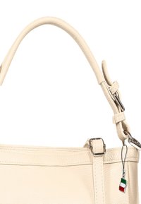 Lichtbeige leren handtas met een gebogen handvat, zilverkleurige accenten en een klein Italiaans vlaggetje als hanger. Soepele textuur, minimalistisch ontwerp.