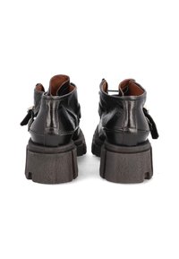 Botas de tobillo de cuero negro con una suela robusta oscura, que cuentan con una pestaña en la parte trasera y acentos de hardware en latón. Textura suave y diseño de corte alto.