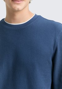 Blauer gerippter Pullover mit Rundhalsausschnitt und strukturiertem Stoff. Verfügt über ein sanftes, eng anliegendes Design, das einen lässigen Stil betont.