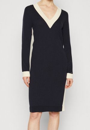 Knit dress featuring a deep V-neck, long sleeves, navy body with ivory side panels, ribbed cuffs, and hem. Simple, fitted silhouette.