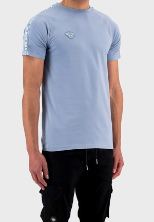 Hellblaues Baumwoll-T-Shirt mit Rundhalsausschnitt, kurzen Ärmeln und Raglan-Design. Verfügt über den Schriftzug "BLACK BANANA" entlang der Ärmel und ein Logo auf der Brust.