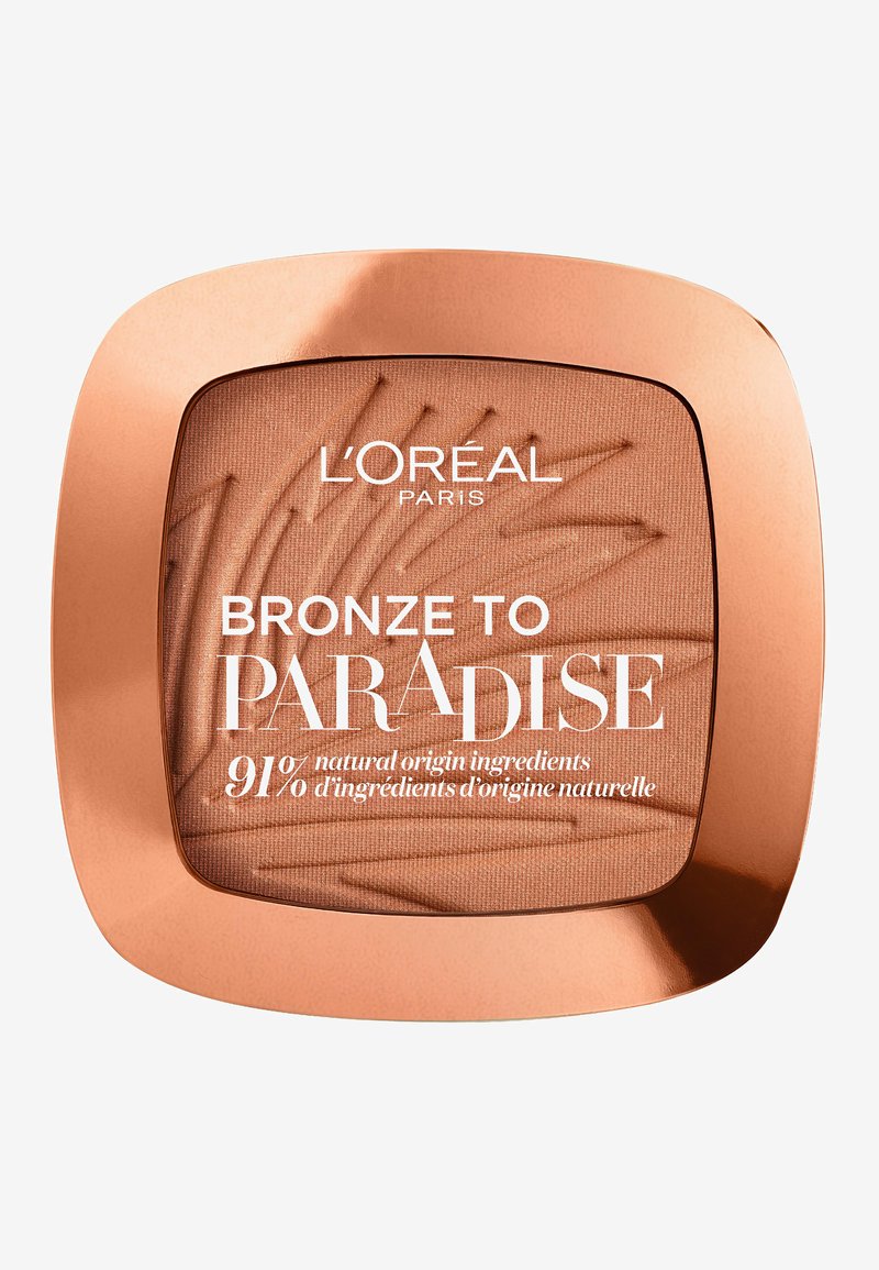 Bronze to Paradise bronzer i en firkantet, rosaguld kompakt. Har en naturligt udseende mat tekstur med et palmebladsmønster. Tekst vises fremtrædende.