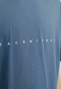 Blaues T-Shirt aus Baumwolle mit weicher Textur. Mit "JACK & JONES" in weißen Buchstaben über der Brust bedruckt. Klassisches Rundhals-Design.