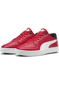 Pantofi sport din piele roșie cu accente albe, o suprafață netedă, un design perforat lângă vârful pantofului și un toc negru. Au detalii cu logo.