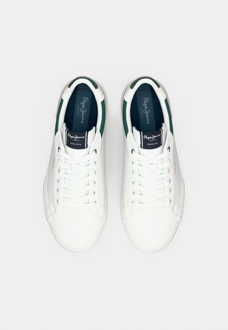 Witte sneakers van een glad synthetisch materiaal, met groene accenten op de hiel en een klassieke vetersluiting. Opvallend logo op de tong.