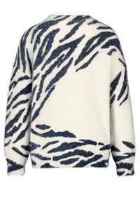 Pull pelucheux crème avec imprimé animalier bleu marine. Présente un col rond et des manches longues, avec des poignets et un ourlet côtelés. Texture moelleuse.