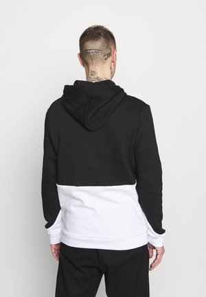 Sudadera con capucha de parte superior negra y sección inferior blanca, con puños de canalé y una textura de tela suave. Capucha ajustable con cordón.