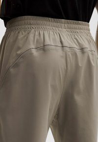 Lichtbeige sportieve broek met een elastische taille, voorzien van gladde stof en subtiele naden aan de zijkanten.