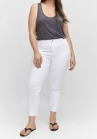 Jeans blancos hasta los tobillos combinados con una camiseta sin mangas gris oscuro y sandalias negras de tipo flip-flop. Tela suave con un diseño ajustado y estilo de cinco bolsillos.