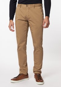 Beige chino's met een slim fit, van katoen, met knoopsluiting, voorzakken en gecombineerd met bruine sneakers met donkere veters.