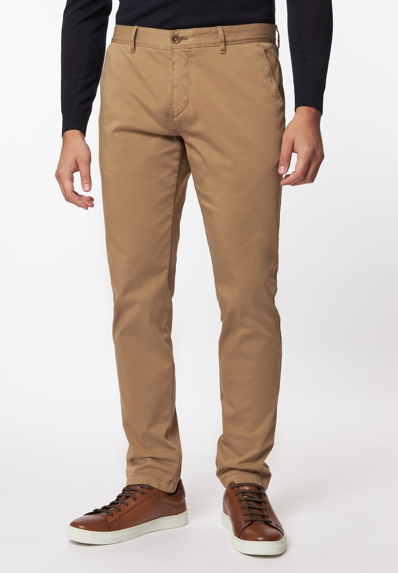 Beige chino's met een slim fit, van katoen, met knoopsluiting, voorzakken en gecombineerd met bruine sneakers met donkere veters.