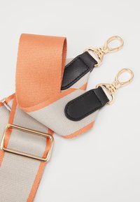Sangle réglable en tissu tissé orange et gris, avec des accents en cuir noir, des clips en métal doré et une boucle rectangulaire.