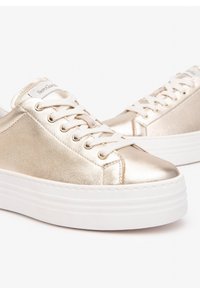 Metallisch goldene Sneaker mit glatter Oberfläche, weißer Plateausohle und Schnürdesign, das goldene Ösen und ein Logotag an der Zunge aufweist.