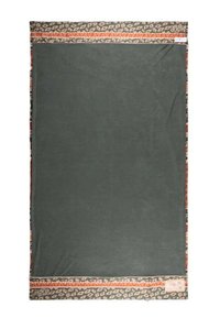 Copriletti verde in morbido tessuto con bordo decorato da forme e accenti arancioni, beige e neri. Texture evidente del materiale.