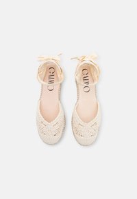 Beige crochet shoes with ankle ribbons, open toe design, and a textured woven pattern on the exterior and sole. Soft inner lining.