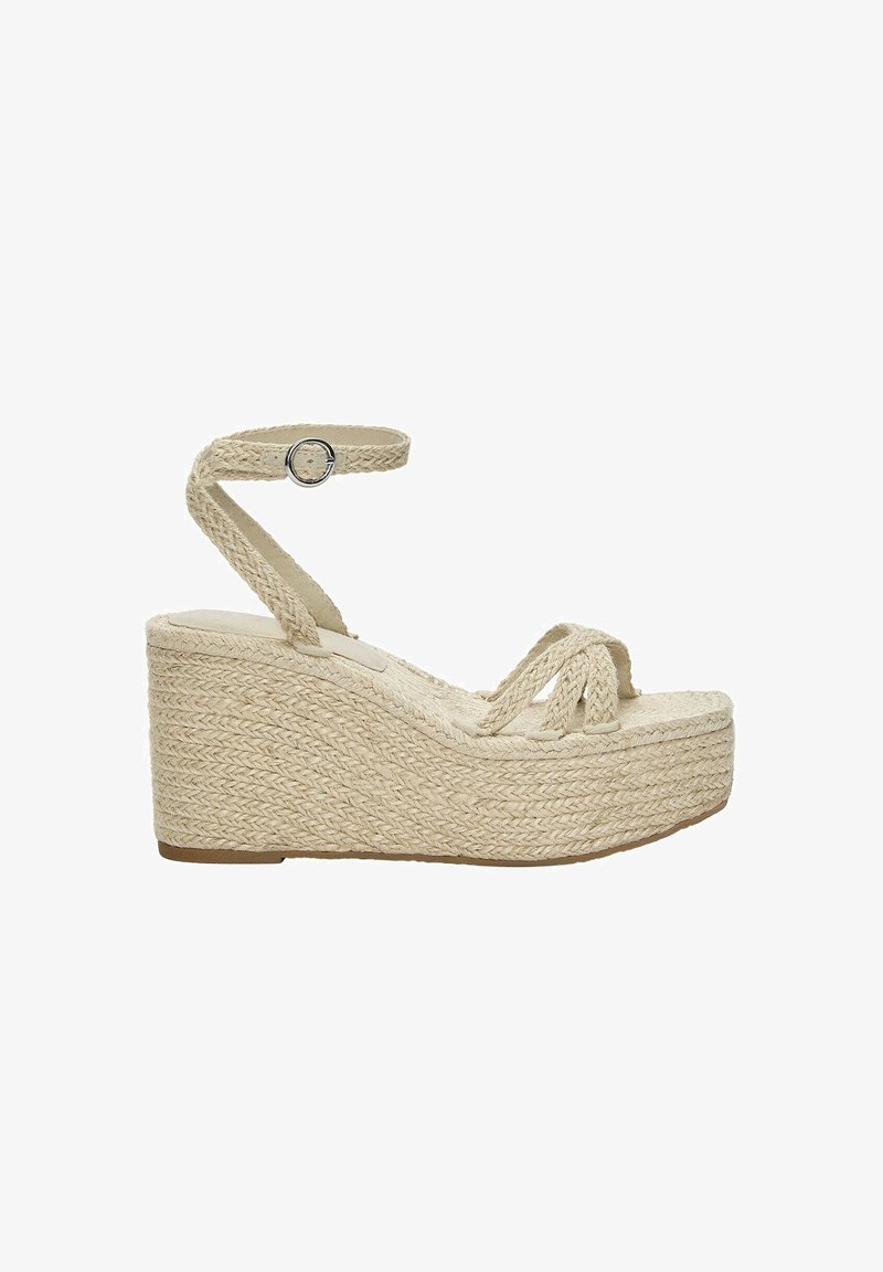 Sandale compensée beige tissée avec bride à la cheville et boucle, texture tressée couvrant le talon compensé et les brides sur les orteils.
