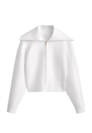 Weiße Zip-Jacke mit großem Kragen, croppter Passform, langen Ärmeln, gerippten Bündchen und dezenten Nähten. Weicher Stoff.