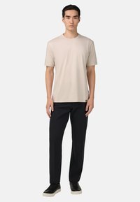 Světle béžové bavlněné tričko s klasickým výstřihem, kombinované s černými kalhotami a černými teniskami. Texturovaná tkanina, volný střih.