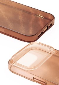 Brązowe etui na telefon z brokatem, zaokrąglonymi krawędziami i wycięciami na ładowanie oraz przyciski. Materiał wydaje się błyszczący i przezroczysty.