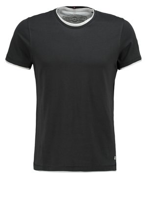 Giacca verde leggera con cappuccio foderato beige, chiusura frontale con cerniera, due tasche frontali e coulisse regolabili, abbinata a jeans chiari e sneakers.