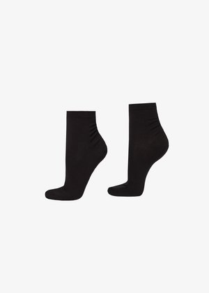 Paire de chaussettes noires montantes, vues de côté sur un fond blanc.