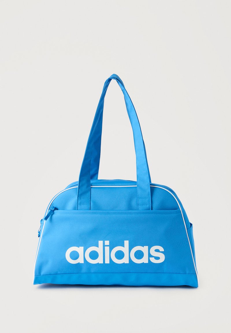 Μπλε αθλητική τσάντα Adidas με δύο λαβές, εμπρόσθια τσέπη με φερμουάρ και λευκή διακόσμηση κατά μήκος των άκρων.