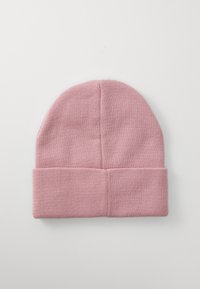 Bonnet en tricot rose avec un revers, posé à plat sur une surface blanche.