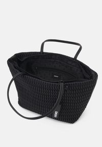 Sac à main noir DKNY avec un extérieur en tissage texturé, deux courtes poignées et une poche intérieure. Design ouvert, détail de marque minimaliste à l'intérieur.