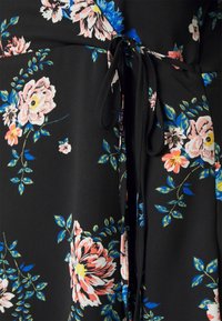 Vestido floral con fondo negro, adornado con flores rosas y azules. Tejido suave, detalle de cintura atada y hojas verdes en todo el diseño.