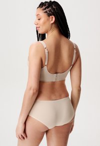 Beige bh och matchande hipsterunderkläder, tillverkade av ett glansigt tyg. Bh:n har justerbara axelband och en hak- och ögonslutning baktill.