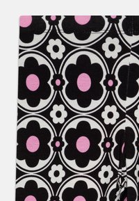 Tela en blanco y negro con un patrón floral que presenta grandes flores negras, centros rosas y acentos blancos, con detalles circulares en toda su extensión.