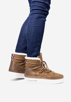 Bottines en suède et cuir marron avec un col en fourrure blanche, lacets et accents rouge, blanc et bleu. Comprend un logo en relief et une semelle blanche.