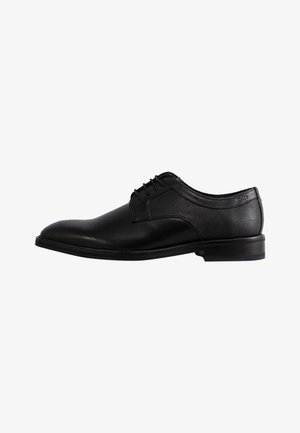 Zwart leren nette schoen met een gladde afwerking, voorzien van een netaccent aan de zijkant, ronde neus en vetersluiting.