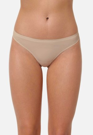 Culotte en tanga beige avec une texture lisse, offre une couverture minimale et une taille basse, conçue pour un ajustement sans couture.