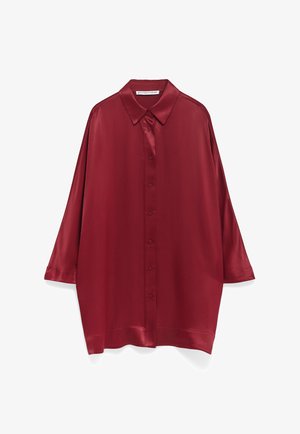 Burgundowa satynowa koszula z kołnierzykiem, długimi rękawami i zapięciem na guziki. Posiada luźny krój i gładką fakturę z minimalnym połyskiem.