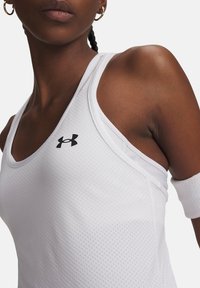 Λευκό αθλητικό τοπ με υφή υφάσματος. Διαθέτει μαύρο λογότυπο Under Armour στην αριστερή πλευρά. Οι λουρίδες είναι λεπτές και χωρίς ραφές.