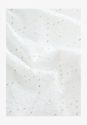 Biała haftowana tkanina z kwiecistymi wzorami i wyciętymi detalami, charakteryzująca się gładką teksturą i lekko opadającym drapowaniem.