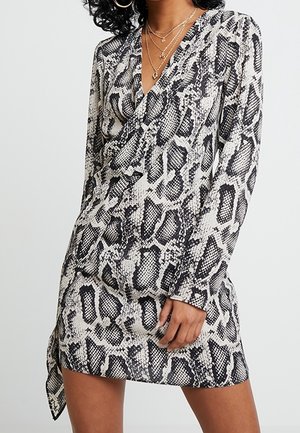 Langærmet kjole i sort og hvidt slangeprint, med dyb V-udskæring og et bundet bælte i taljen for en figursyet silhuet.