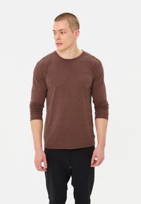 Bruine lange mouwen shirt gemaakt van zachte stof, met een ronde halslijn, een aansluitend ontwerp en een klein logo op de borst.