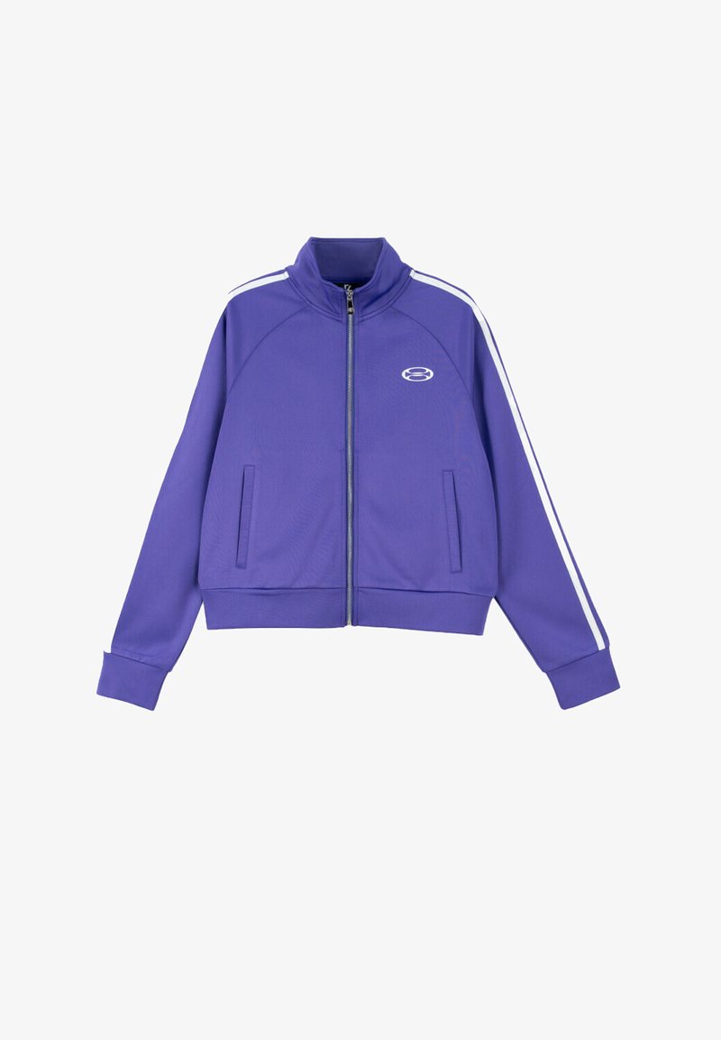 Fioletowa kurtka na zamek wykonana z gładkiego, elastycznego materiału. Posiada białe paski po bokach oraz dwie przednie kieszenie; wysoki kołnierz i ściągacze na mankietach.