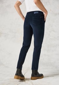 Marineblauwe, slim-fit spijkerbroek met achterzakken en een label op de tailleband, gecombineerd met zwarte chelsea laarzen met een chunky zool.