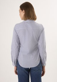 Gestreiftes Hemd in Blau und Weiß, mit einem Button-Down-Kragen, langen Ärmeln und einem abgerundeten Saum, aus leichtem Stoff gefertigt.