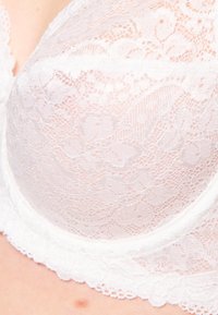 Witte kant bh met bloemenpatronen, met een zachte, semi-doorzichtige textuur en een gekartelde kantafwerking langs de cups.